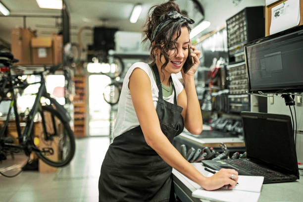 beautiful young female bicycle mechanic working on a customer bicycle